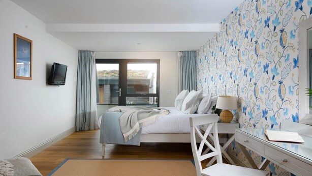 A bedroom with a bed, a desk, a chair, a television, and a window with curtains. - 2 Bed in Watergate Bay (oc-b584340) (Tregurrian)