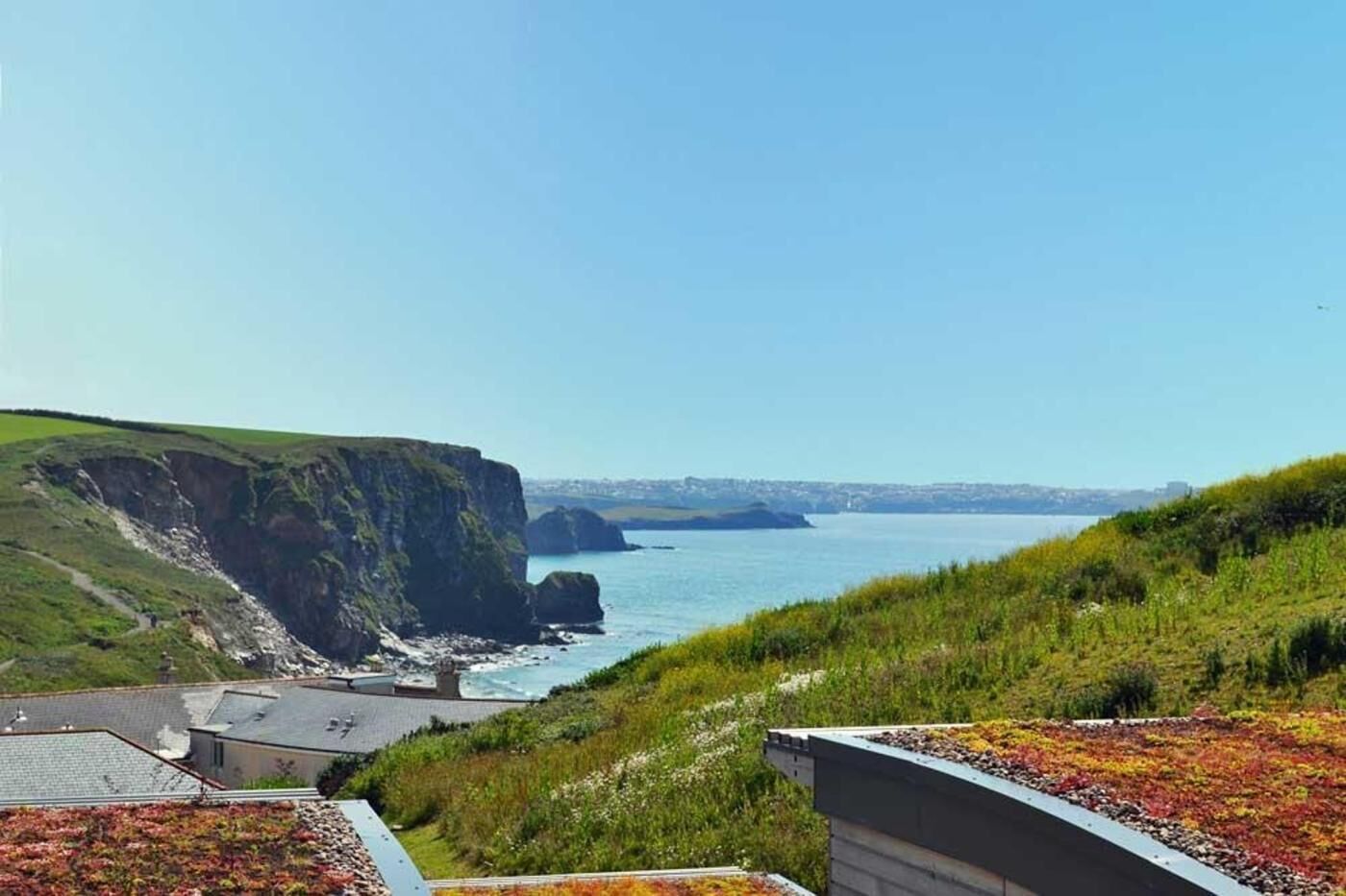A coastal landscape with cliffs, a body of water, and a clear sky.