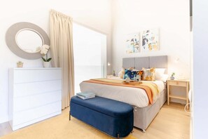 A bedroom with a bed, bedside tables, a dresser, a mirror, and artwork on the wall. - 3 Bed in Hayle (oc-b635644) (Hele)