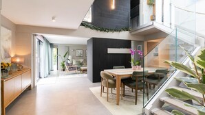 A modern interior with a dining area, a staircase, and a living space. - 3 Bed in Downderry (oc-b652220) (Downderry)