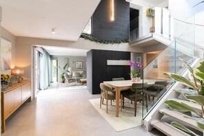 Um interior moderno com área de jantar, escada e espaço de estar.