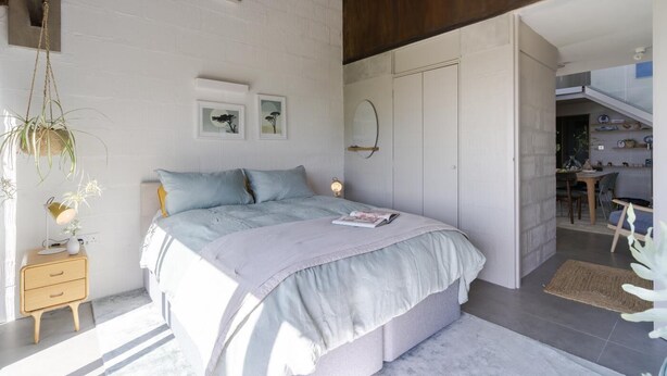 A bedroom with a bed, bedside tables, a hanging plant, and a view into the dining area. - 3 Bed in Downderry (oc-b652220) (Downderry)