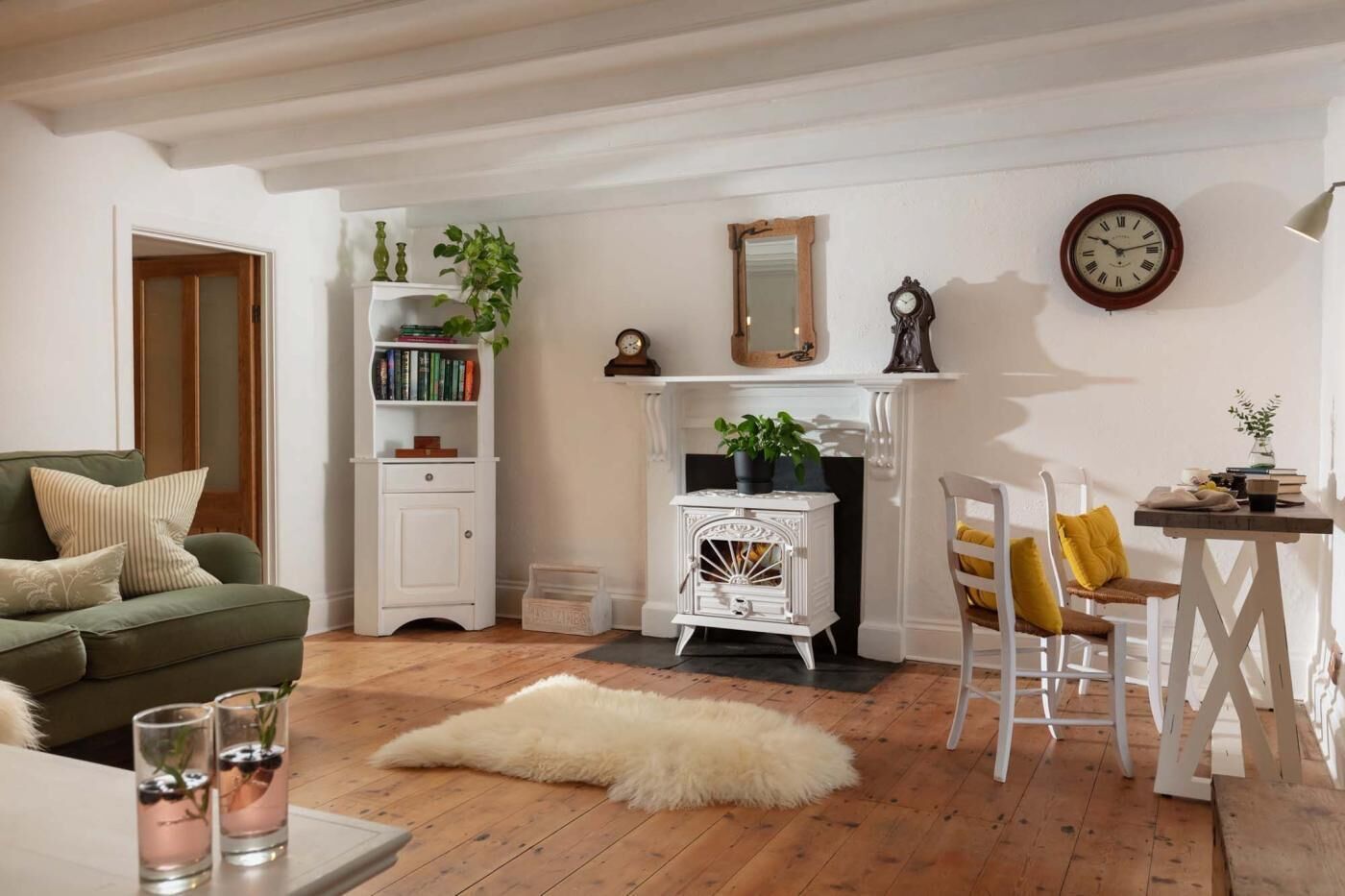 A cozy living room with a fireplace, a bookshelf, a green sofa, and a dining area with a table and chairs.