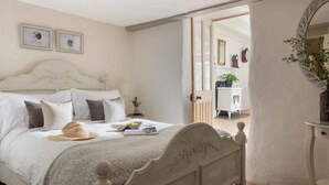 A bedroom with a bed, bedside table, and a mirror. There are framed certificates on the wall. - 5 Bed in Holywell Bay (oc-b614951) (Cubert)