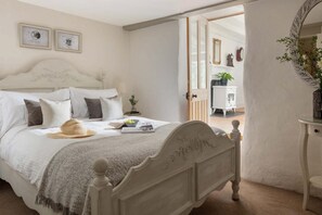 Ein Schlafzimmer mit einem Bett, Nachttisch und Spiegel. An der Wand hängen gerahmte Zertifikate.