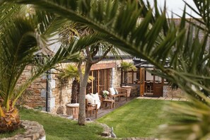 A stone building with a patio area, outdoor seating, and a well-maintained lawn. - 5 Bed in Holywell Bay (oc-b614951) (Cubert)