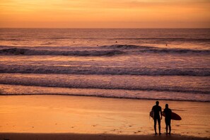 Eine Strandansicht mit Wellen und einem Sonnenuntergang.