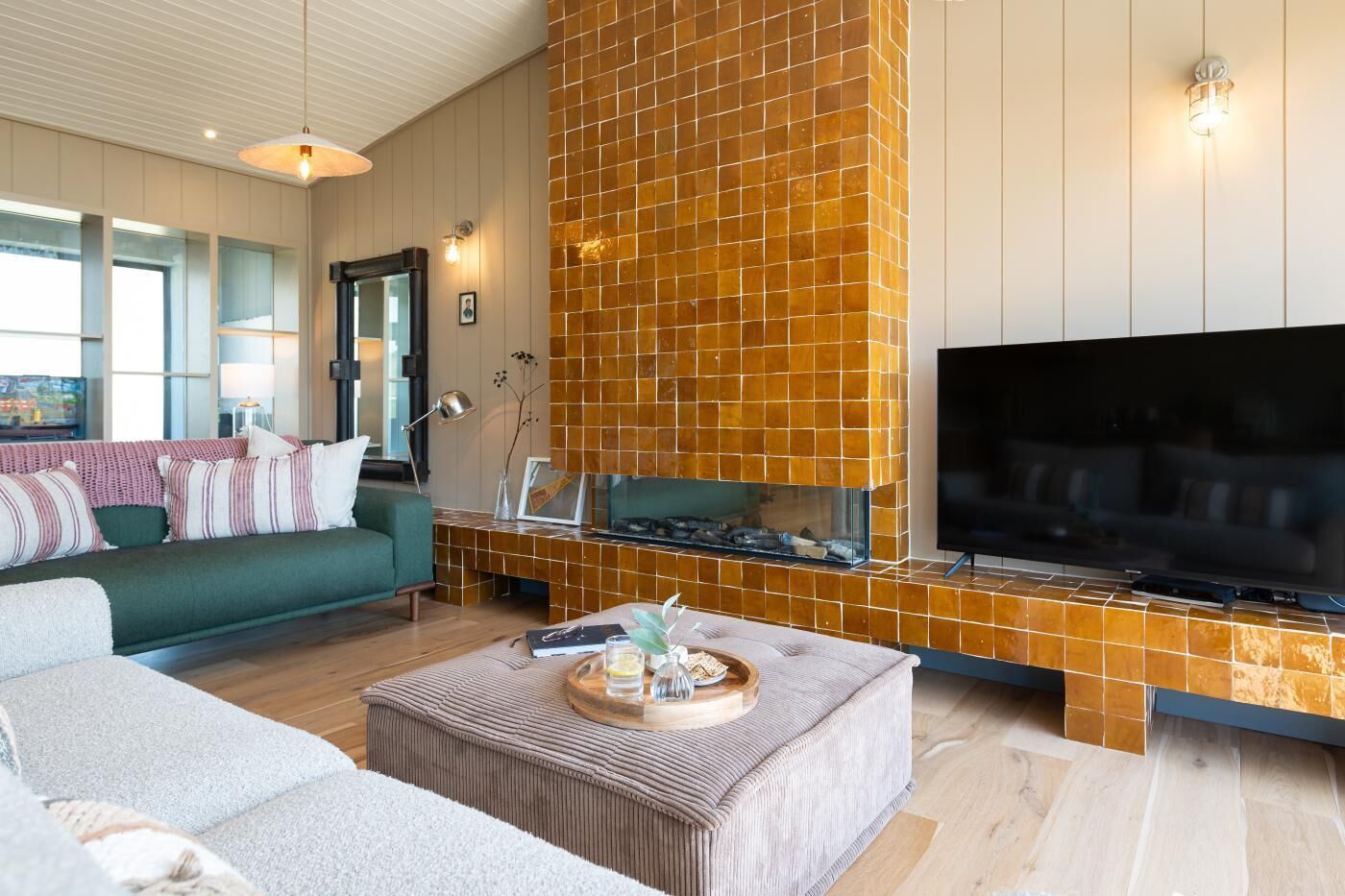 Ein modernes Wohnzimmer mit großem Flachbildfernseher, Kamin und einer Couch.