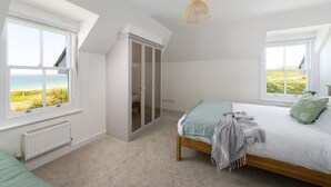 A bedroom with a bed, two windows, a wardrobe, and a hanging light fixture. - 2 Bed in Fistral (oc-b625209) (Newquay)