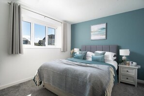 Ein Schlafzimmer mit einem Bett, Nachttischen, einem Fenster und einem Bild an der Wand.
