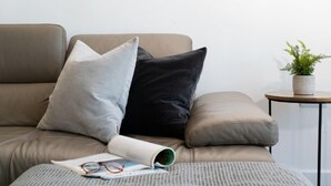 A sofa with two pillows, a small table with a plant, and a magazine with glasses on it. - 3 Bed in Fistral (oc-b595429) (Newquay)