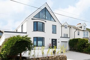 A modern two-story house with a prominent triangular roof, large windows, and a stone foundation. - 5 Bed in Carbis Bay (oc-b623959) (Carbis Bay)