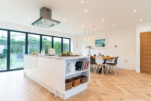 A modern kitchen with a large island, dining area, and large windows. - 5 Bed in Carbis Bay (oc-b623959) (Carbis Bay)