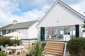 A modern house with a dining area, outdoor seating, and a staircase leading to the entrance. - 5 Bed in Carbis Bay (oc-b623959) (Carbis Bay)