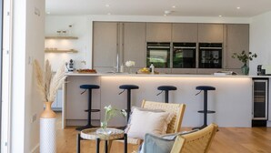 Une cuisine moderne dotée d’un îlot central, de tabourets de bar et d’un coin repas avec une table ronde et des chaises.
