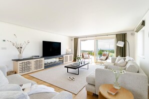 A modern living room with a flat-screen TV, a fireplace, a sofa, and a dining area. - 5 Bed in Sennen (oc-b622152) (Trewolla)
