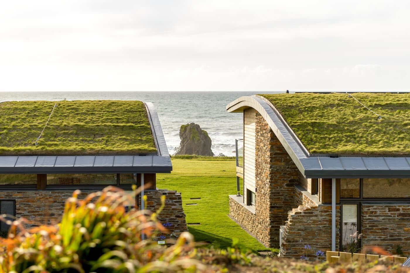 Une propriété située sur la côte, avec des toits couverts d’herbe, des murs en pierre et une vue sur la mer.