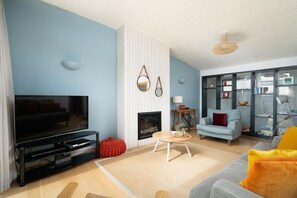 Ein modernes Wohnzimmer mit Flachbildfernseher, Kamin, Sofa und Bücherregal.