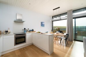Eine moderne Küche mit weißen Schränken, einem eingebauten Backofen und einem Essbereich mit Tisch und Stühlen.