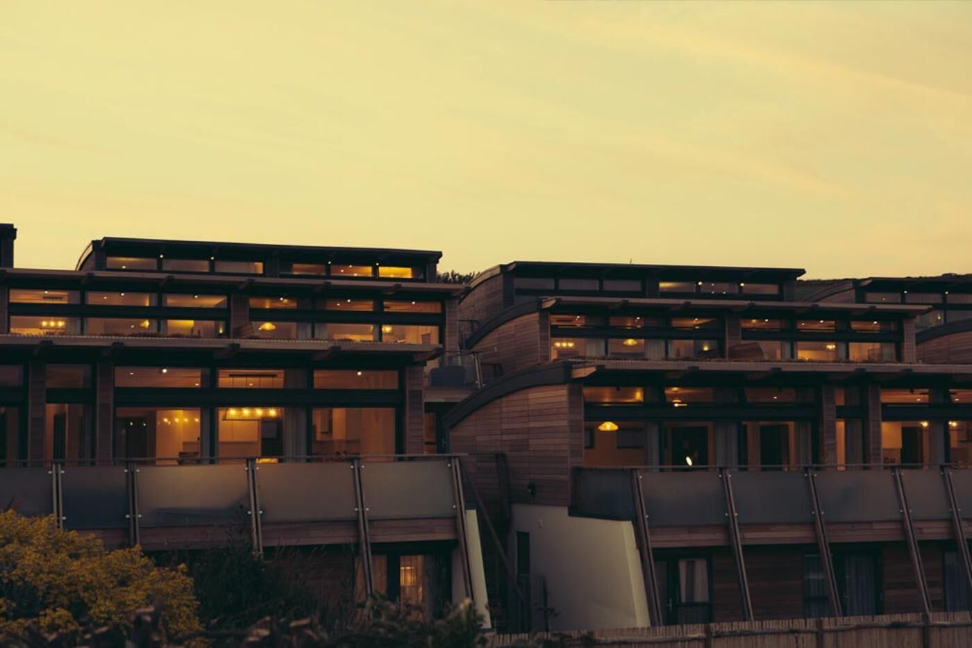 Een hotel met meerdere verdiepingen, balkons en grote ramen.