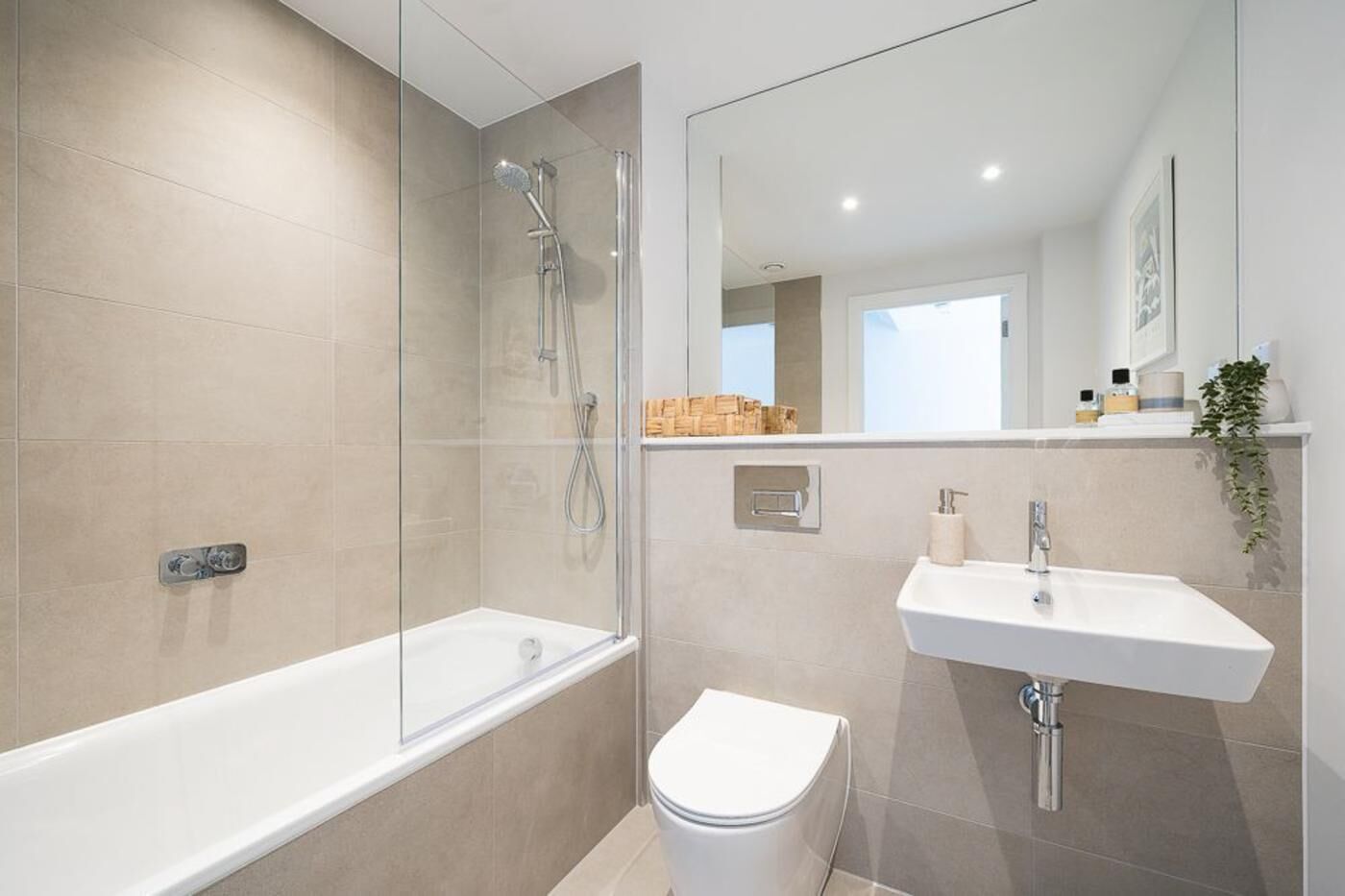 A modern bathroom with a glass-enclosed shower, a white bathtub, a white toilet, and a white sink with a mirror above it.