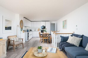 Um apartamento moderno com área de jantar, cozinha compacta e sala de estar com sofá e mesa de centro.