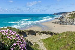 A coastal landscape with a beach, rocky cliffs, and a clear sky. - 2 Bed in Porthtowan (oc-b584420) (Porthtowan)