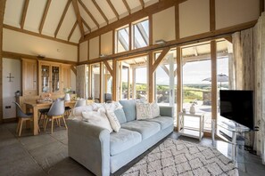 Un salon spacieux avec un grand canapé, un coin repas doté d’une table en bois et un téléviseur.