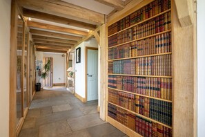 A hallway with a wooden ceiling, a bookshelf filled with books, and a door at the end. - 3 Bed in Widemouth Bay (oc-b581851) (Rosecare)