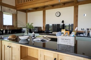 A kitchen with a wooden countertop, a clock, and a basket labeled 'FARM PRODUCE.' - 3 Bed in Widemouth Bay (oc-b581851) (Rosecare)