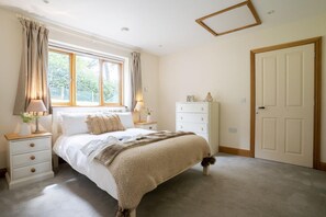 Une chambre à coucher avec un lit, des tables de chevet, une commode et une porte.