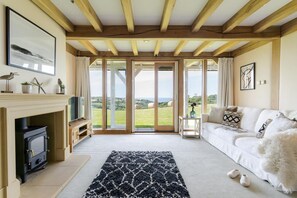 Ein gemütliches Wohnzimmer mit Kamin, einer Couch und Blick ins Grüne.