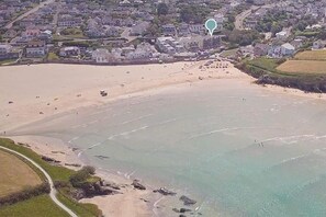 Luftaufnahme einer Küstenlandschaft mit Strand, Wohngebäuden und einer Straße.