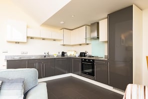 Eine moderne Küche mit dunklen Schränken, einem eingebauten Backofen und einer Arbeitsplatte aus Granit.