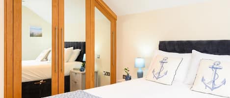 Ein Hotelzimmer mit einem Bett, einem Nachttisch, einer Lampe und einem Schrank mit Spiegeln.