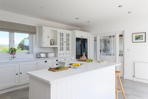 A modern kitchen with white cabinetry, a large island, and a view of the outdoors. - 4 Bed in Charlestown (oc-b610558) (Charlestown)