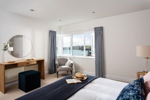 Une chambre à coucher avec un lit, un bureau, une chaise, une fenêtre avec des rideaux et une lampe.