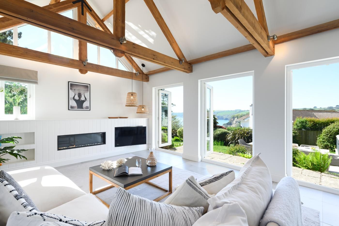 A modern living room with a fireplace, large windows, and a view of the outdoors.