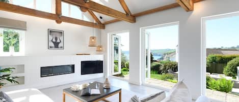 Una sala moderna con chimenea, ventanas amplias y vistas al exterior.