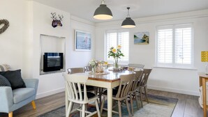 A dining area with a wooden table, chairs, and pendant lights. - 4 Bed in Trevone (oc-b637403) (Trevone)