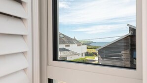 A window with a view of a coastal area, including houses and a clear sky. - 4 Bed in Trevone (oc-b637403) (Trevone)