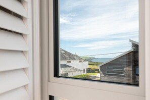 Ein Fenster mit Blick auf eine Küstenlandschaft, darunter Häuser und ein klarer Himmel.