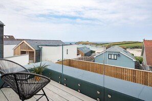 Ein Balkon mit Blick auf einen Strand und Häuser, ausgestattet mit einem Stuhl und einem Blumentopf.