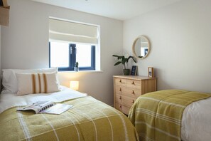 Ein Schlafzimmer mit Bett, Nachttisch, Kommode, Fenster und Spiegel.