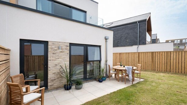 Een modern huis met een terras, een eethoek en een groot raam.