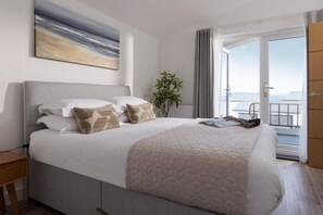 A hotel room with a large bed, a view of the sea, and a balcony. - 4 Bed in Falmouth (oc-b588809) (Goldenbank)