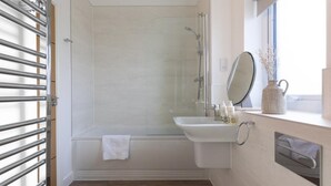 Ein Badezimmer mit Dusche, Waschbecken und Fenster.