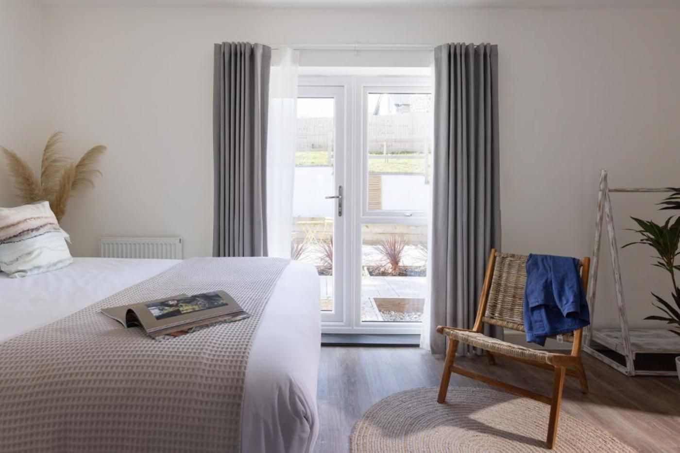 A bedroom with a bed, a chair, a radiator, and a view through a glass door.