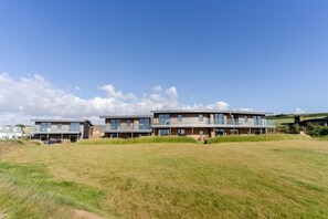 A modern two-story residential building with a flat roof, large windows, and a covered patio area. - 5 Bed in Widemouth Bay (oc-b628538) (Widemouth Bay)