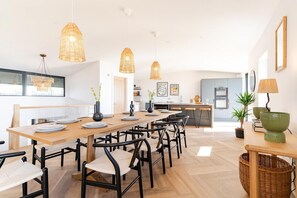 A modern dining area with a wooden table, black chairs, and woven pendant lights.
